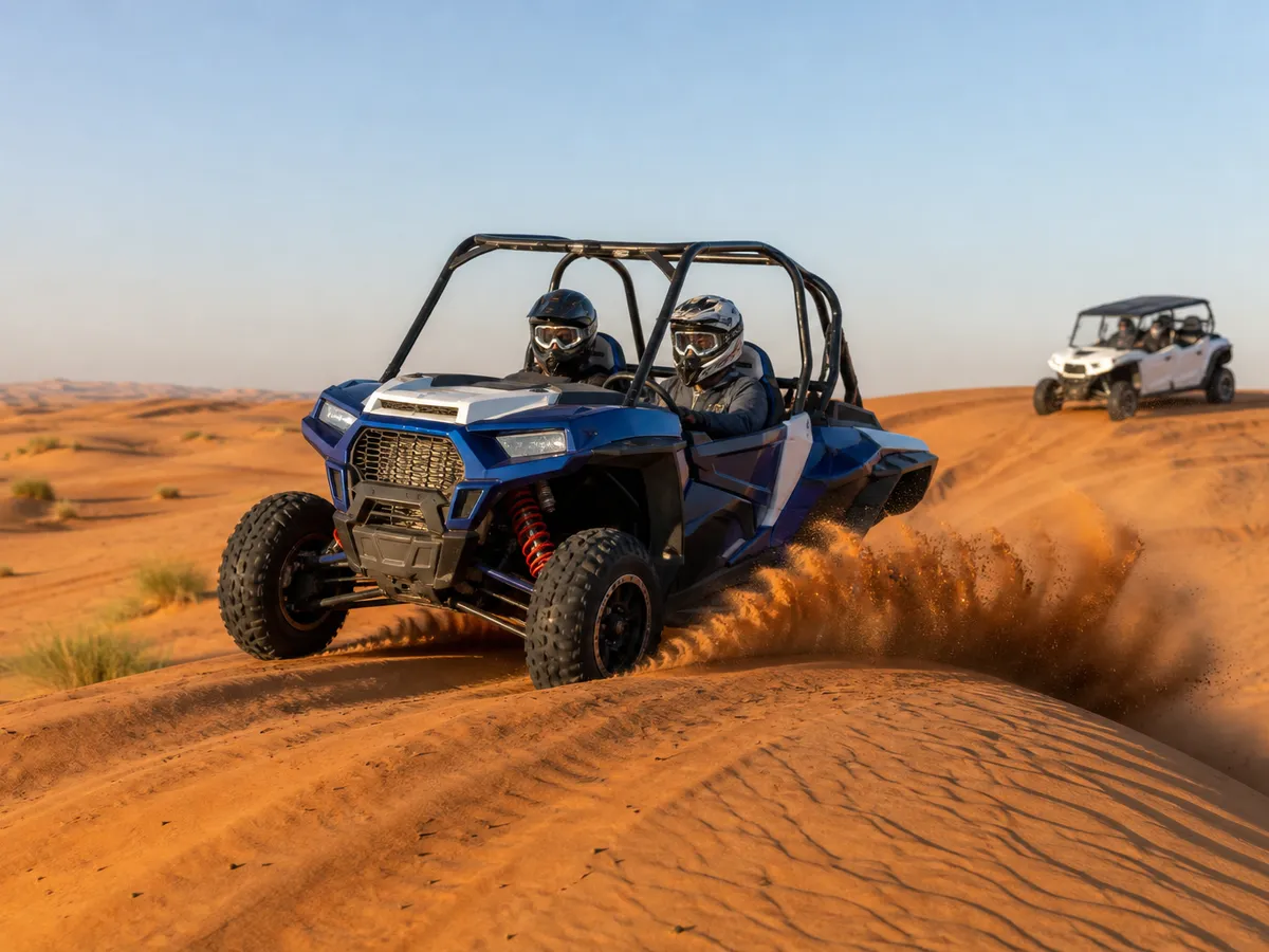 Dune buggy Dubai: two riders in helmets drive a blue 2-seat buggy over the red dunes, a 4-seat buggy following behind