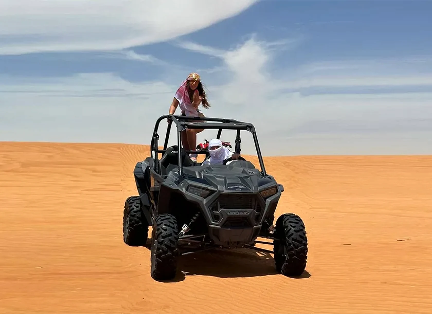 Polaris RZR dune buggy kicking up sand across the Lahbab red dunes near Dubai