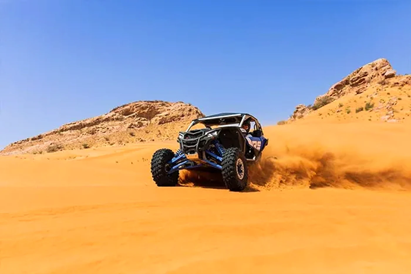 Riders beside a Polaris RZR buggy in the Dubai desert