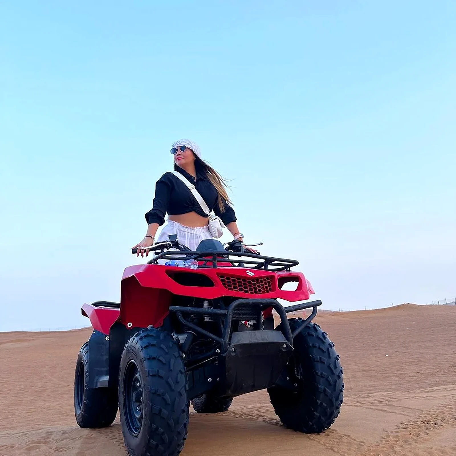 Rider on a red quad bike across the golden Dubai desert dunes - quad biking Dubai