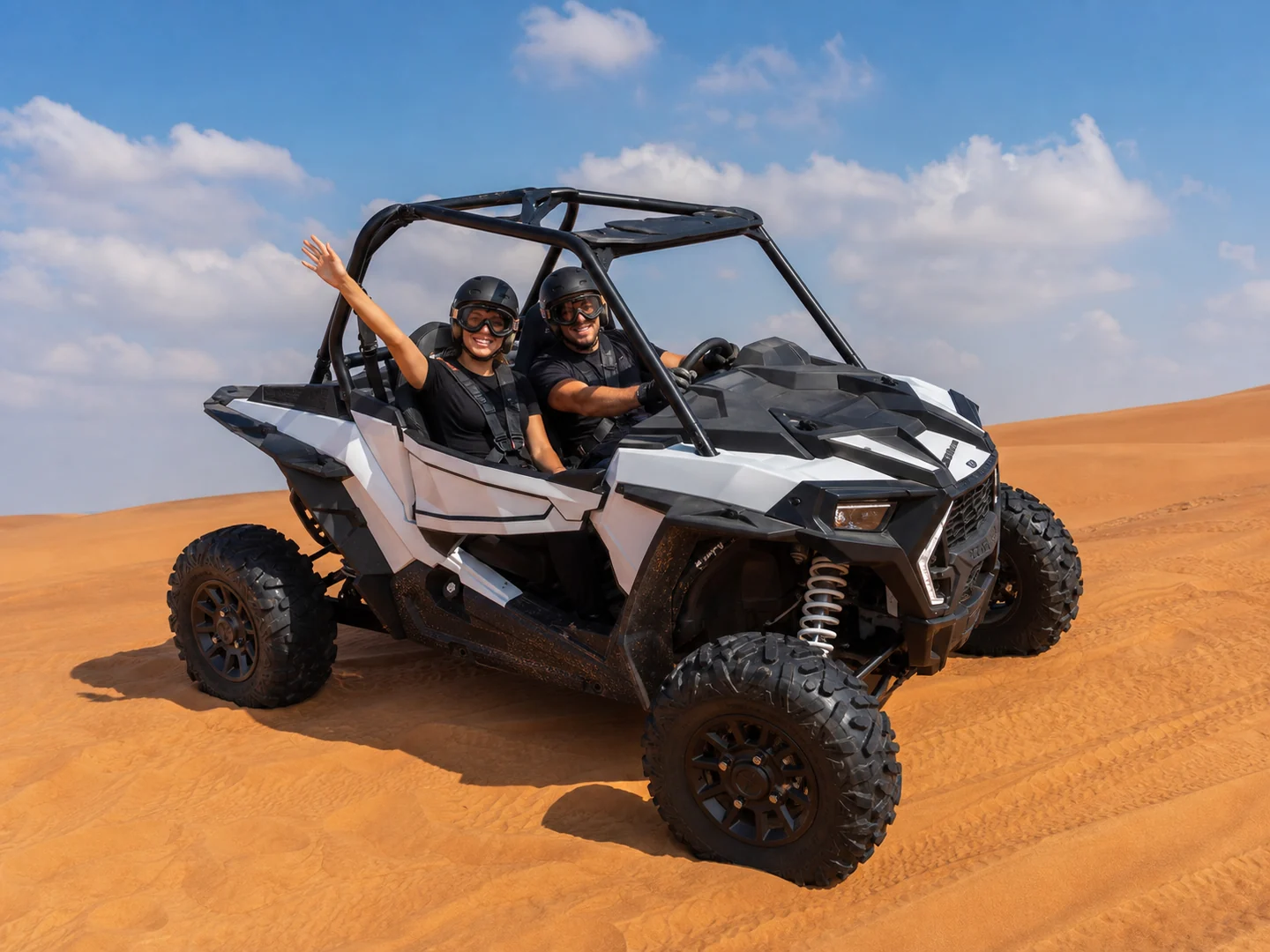 Two-seat dune buggy with helmeted riders on the Lahbab red dunes in Dubai