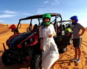 Tourists driving powerful dune buggies across the vast, golden sand dunes of the Dubai desert under a clear blue sky