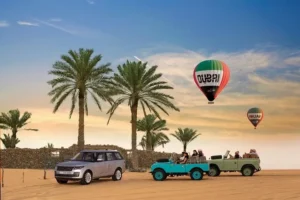 Hot air balloon with the logo 'Balloon Adventures Dubai' floating above the Dubai desert at sunrise, with other balloons in the distance