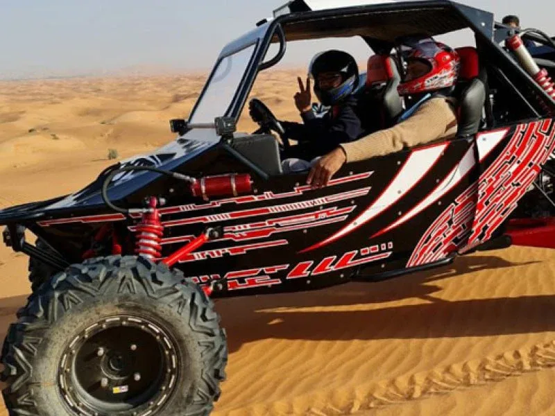 Tourists riding dune buggies across red Dubai dunes at sunset, experiencing the thrill of off-road adventure