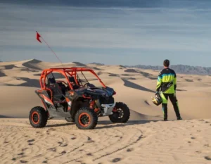 Tourists riding dune buggies across the vast, red Dubai desert at sunset, exploring hidden valleys and natural wonders.
