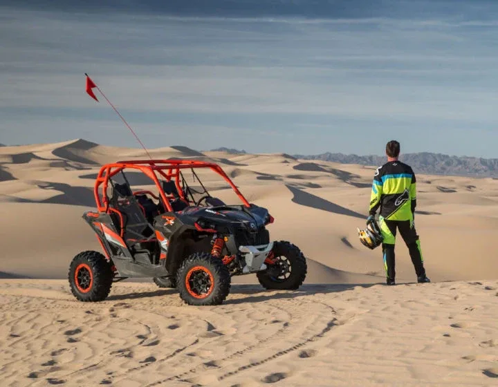 Tourists riding dune buggies across the vast, red Dubai desert at sunset, exploring hidden valleys and natural wonders.