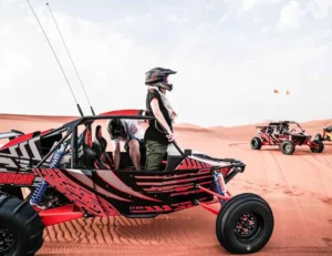 Tourists enjoying an evening desert safari in Dubai with a 4x4 vehicle on the dunes at sunset