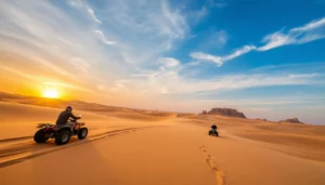 Tourists riding quad bikes across the golden dunes of Algeria's Djanet Desert at sunset, with a vast desert landscape in the background