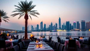 Candlelit waterfront fine dining tables under palm trees facing the Dubai skyline across the water at dusk