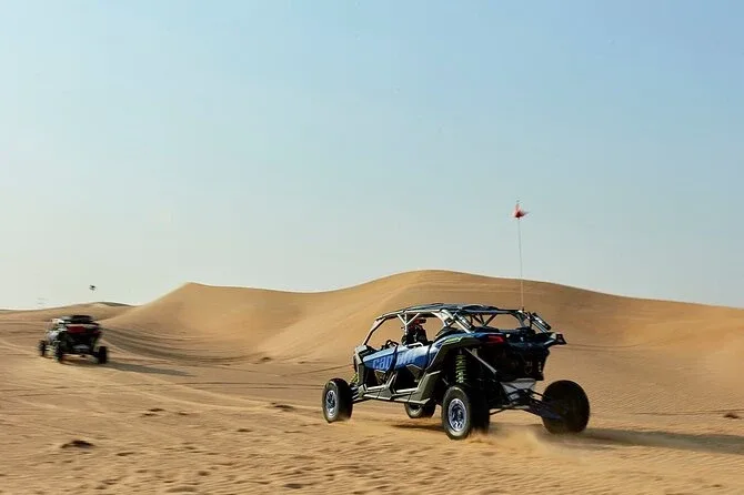 Tourists riding dune buggies across the vast expanse of the Dubai desert, kicking up sand as they navigate the challenging terrain