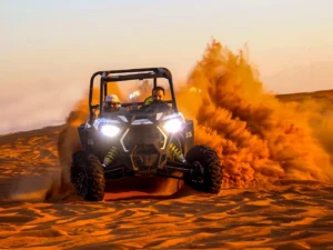 Tourists driving two-seater dune buggies across the vast, golden desert landscape of Dubai under a clear blue sky