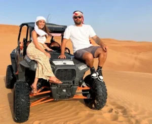 Tourists riding quad bikes across golden sand dunes in Dubai's desert, kicking up sand in an exhilarating desert safari experience