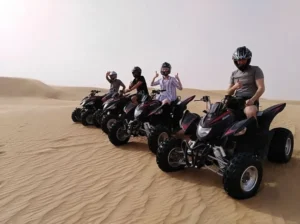 Tourists riding dune buggies across red Dubai dunes at sunset with a hot air balloon in the distance