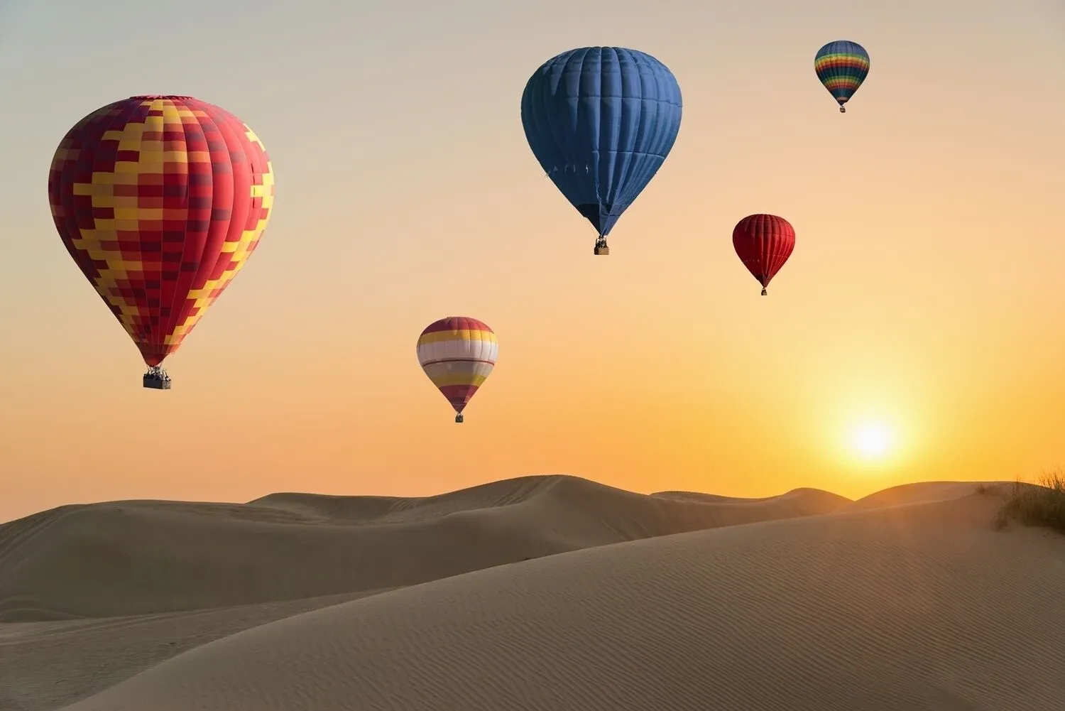 Hot air balloons floating over the Dubai desert at sunrise with the city skyline in the distance, offering a breathtaking view.