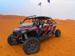 Tourists riding dune buggies across red Dubai dunes at sunset, enjoying an exhilarating off-road desert adventure