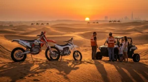 Two dirt bikers, one on a KTM and one on a regular dirt bike, riding side-by-side across the red sand dunes of Dubai's desert.