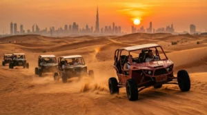 Tourists riding dune buggies across red Lahbab dunes at sunset, with a lead guide setting the pace and a support vehicle following closely behind