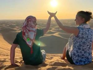 Tourists on a morning desert safari in Dubai, witnessing the sunrise over the golden sand dunes of the Arabian desert