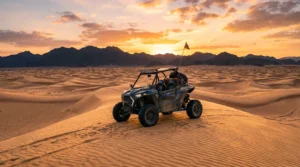 Dune buggy on Ras Al Khaimah desert dunes at sunset with mountains on the horizon