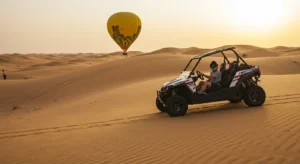 Hot air balloon drifting over Dubai desert dunes at sunrise above golden sand