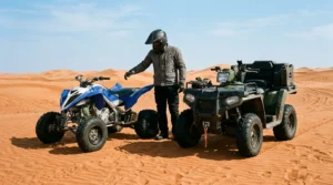 4 wheeler vs quad: a sport quad and a utility ATV parked side by side on red desert dunes near Dubai