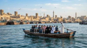 Passengers riding a traditional abra across Dubai Creek past heritage wind-tower buildings in the morning